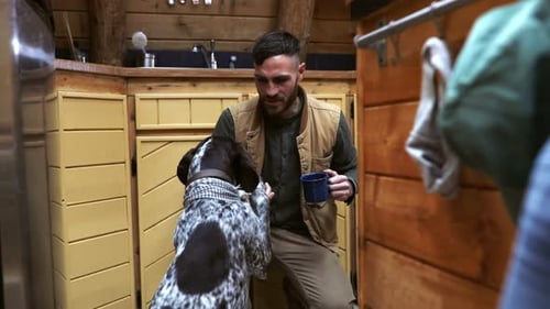 Man Bonding with Dog Inside Rustic Wooden Cabin