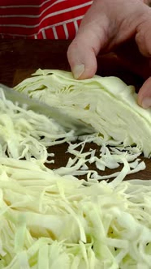 Chef Hands Slicing White Cabbage with Sharp Knife Into Pieces on Chopping Board