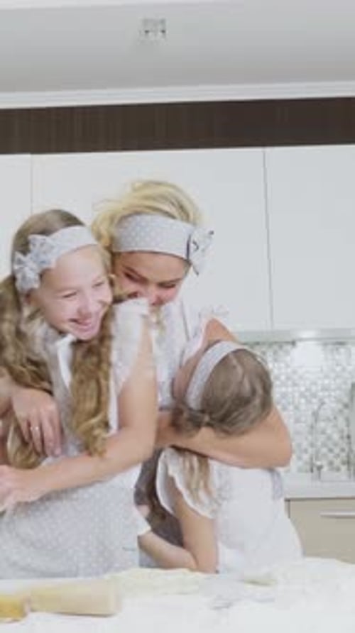 Mère et filles cuisent joyeusement ensemble dans une cuisine lumineuse avec de la farine et un rouleau à pâtisserie