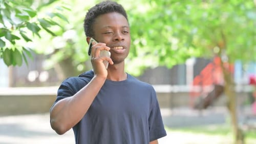 Casual African Man Talking on a Smartphone in a Park