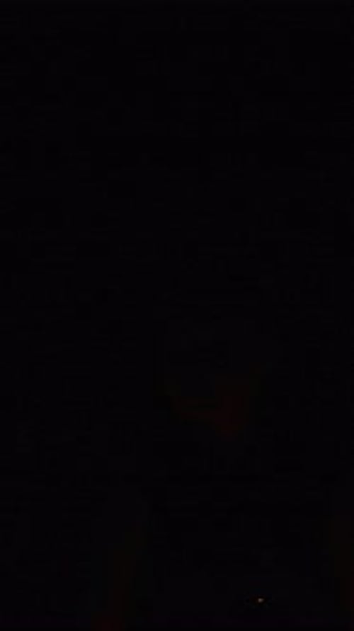 Fire Performer in Dramatic Darkness Spinning Blazing Flames While Wearing a Leather Vest During an