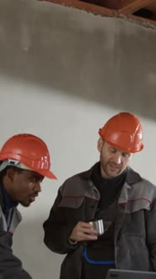 Construction Engineers Reviewing Project Plan on Laptop at Construction Site