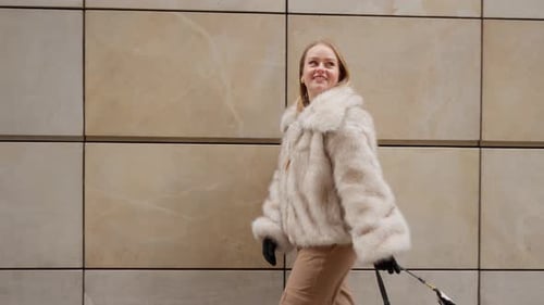 A woman in a stylish fur coat walking in a city on a mild winter day