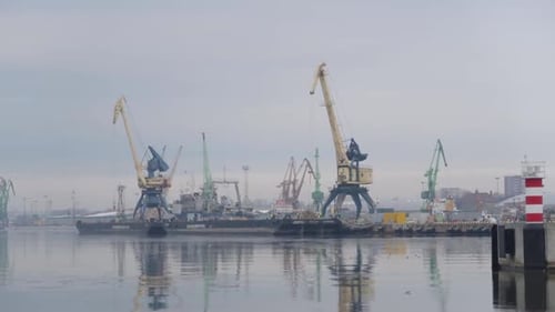 industrial port seen from distance with tall cranes and icy cold water with moody cloudy sky