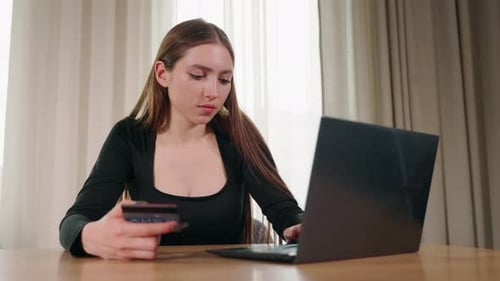 Young Woman Making an Online Payment with a Credit Card While Using a Laptop at Home