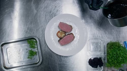 Chef Plating Beef Dish with Sauce and Greens