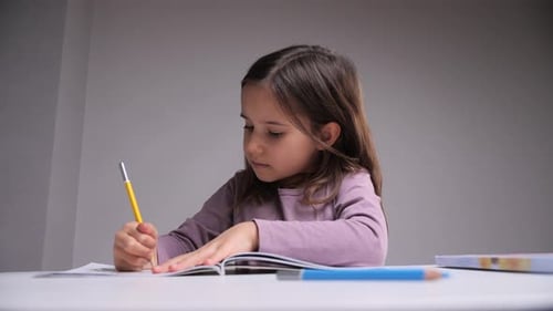 Young Girl Drawing with a Pencil Indoors