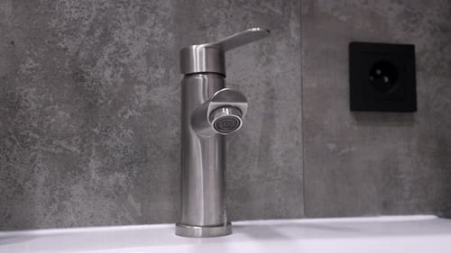 Dripping water faucet close up: plumbing issues and water conservation