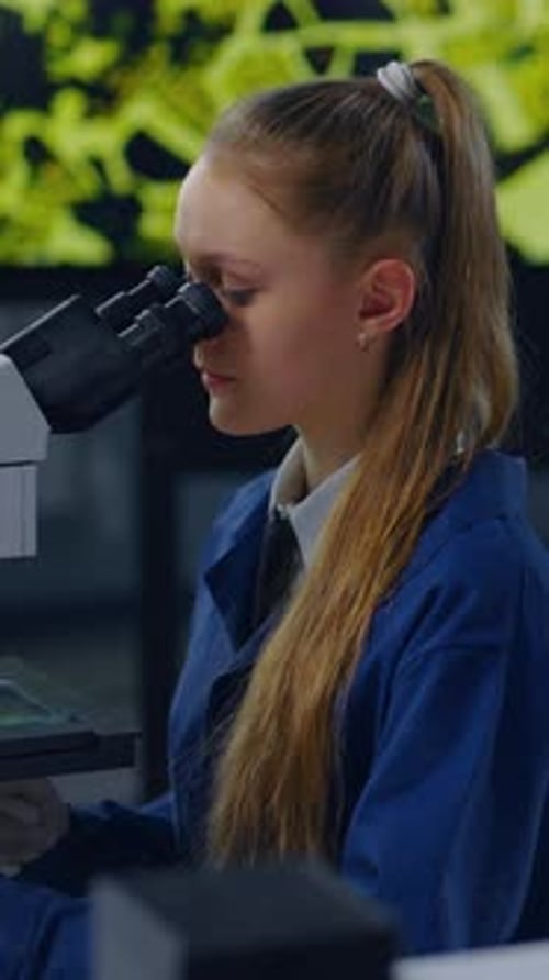 Teen Girl Works with Microscope in Science Lab