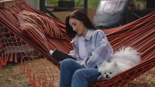Woman Reads in Hammock with White Dog
