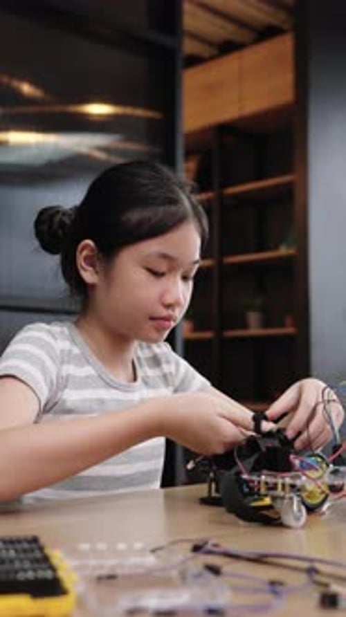 Girl Working on Robot at Table Indoors