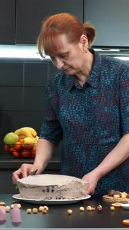 Woman Smooths Cake Frosting in Kitchen