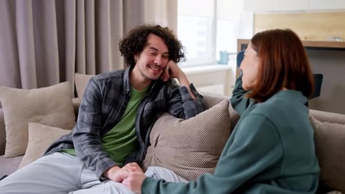 Affectionate Couple Holding Hands on Sofa at Home