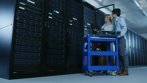 In the Modern Data Center: Engineer and IT Specialist Work with Server Racks, on a Pushcart Equipme