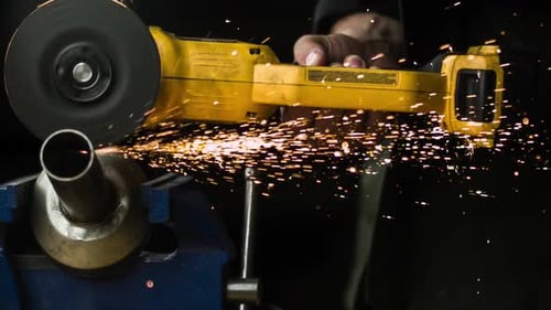 Worker's Hand Holding And Using Handheld Angle Grinder To Cut Metal On Clamp Tool. - close up, slow