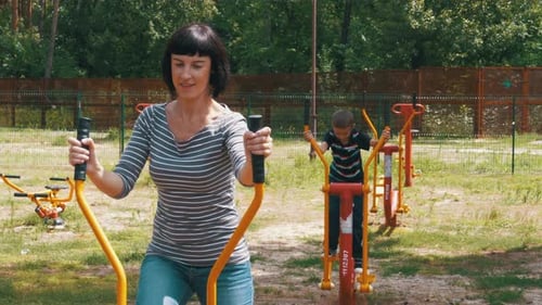 Woman and Child Using Outdoor Fitness Equipment