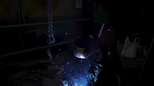 Industrial Worker Welding Metal in Dark Factory
