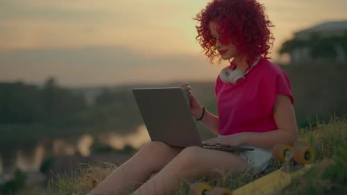 Woman Works on Laptop Outdoors at Sunset