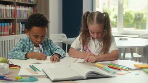 Zwei Schulkinder mit Vielfalt, multiethnische kleine Kinder, gemischtrassige Schüler, die Hausaufgaben schreiben, lernen