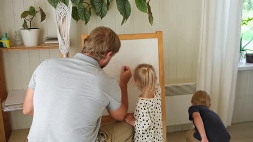 Father Drawing with Children at Whiteboard Indoors