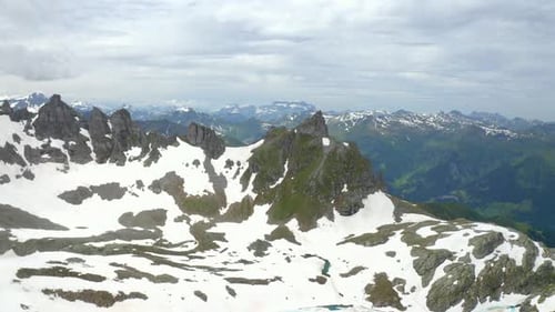 Images aériennes d'un vol au-dessus du sommet d'une montagne révélant une vaste vallée enneigée de montagnes escarpées