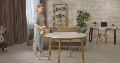 Woman Sprays Cleaner on Wooden Table Indoors
