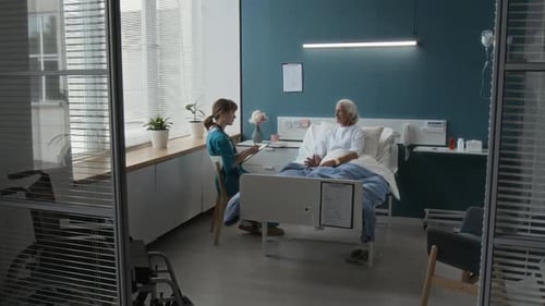 Elderly Patient Telling Doctor about Her Illness Sitting in Bed in Hospital Room