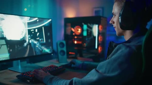 Teenage boy plays video game on computer at home