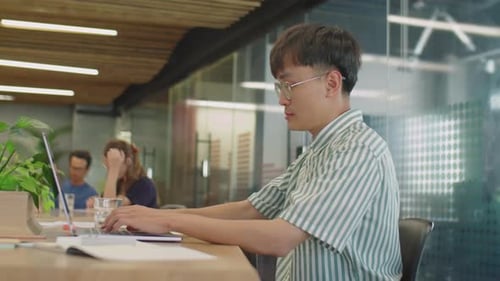 Young Adult Working on Laptop in Modern Office