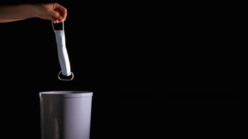 Dropping Mask Into Trash Can on Black Background