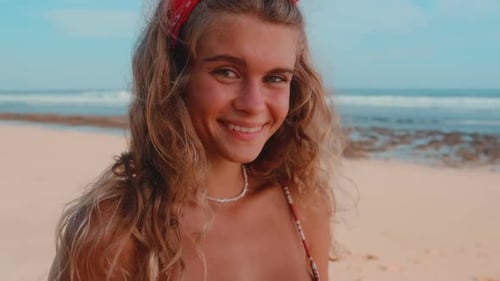 Une jolie adolescente caucasienne joue avec des supports de caméra amusants sur une plage de sable