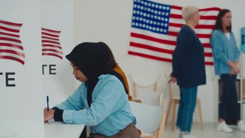 Muslim Woman in Hijab Filling out Ballot in Booth at Electoral Ward