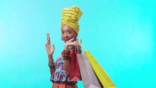 A Stylish Woman in Colorful Attire and an Elegant Headwrap Poses Against a Blue Background