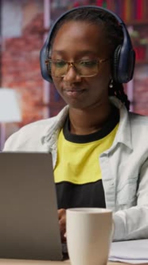 Young Adult Using Laptop Wearing Headphones at Home