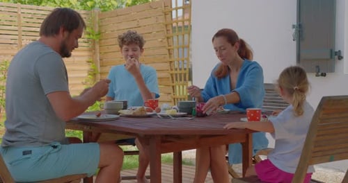 Family Enjoys Meal Together Outdoors on Sunny Day