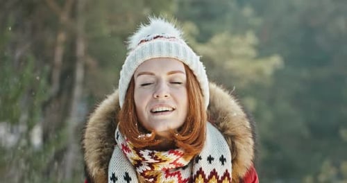 Happy Woman Blowing Snow in Winter Forest