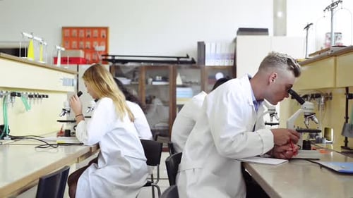High school students discovering scientific breakthroughs with microscopes in the lab