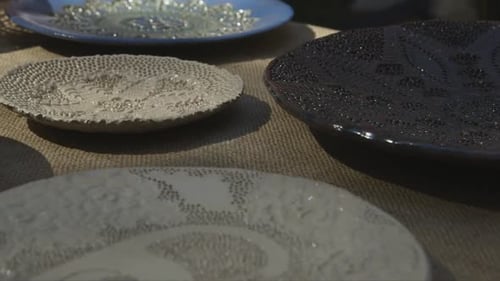 high quality colorful clay plates at artisan market with moving foliage shadows