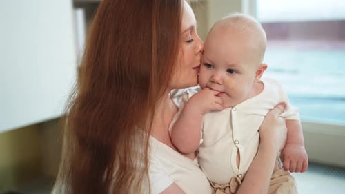 Woman Holding and Kissing Baby Indoors