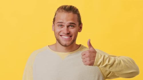 Smiling Man Giving Thumbs Up on Yellow Background