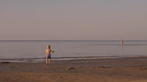 A Serene and Calming Sunset at the Beach Where Children Joyfully Play in the Inviting Water During