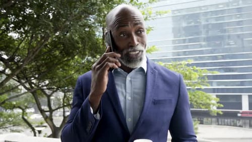 Afroamerikanischer Senior tritt mit Kaffee auf den Balkon und hebt Telefon bei Arbeitsgespräch lächelnd