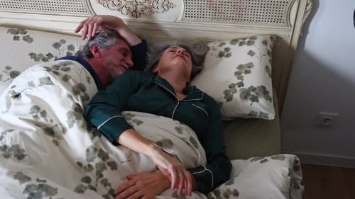 Senior Couple Waking Up in Bed Together Indoors