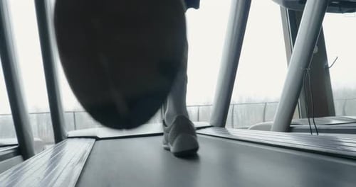 gros plan des jambes d'un garçon qui reste en forme et dont les muscles sont définis ou qui maigrissent, court sur la bande de course