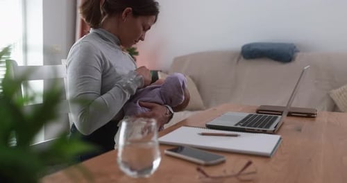 Mother Holding Baby Near Laptop on Wooden Table