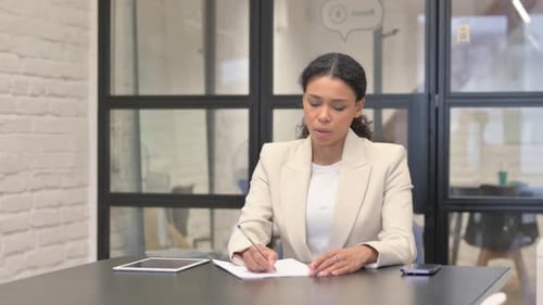 African Business Woman Writing a Letter in Office