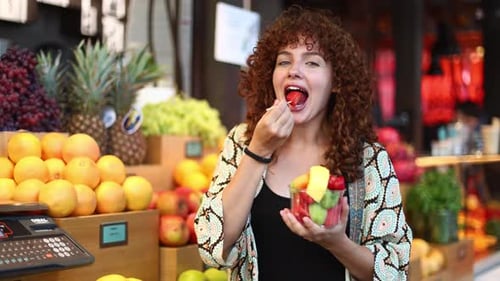 Mujer disfrutando de ensalada de fruta fresca en el mercado