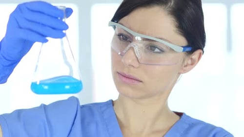 Un chercheur scientifique examine une solution bleue dans un flacon en laboratoire