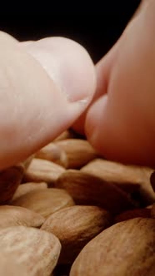 Vertical video. POV, Two Hands Scoop Up a Handful of Almonds Together. Dolly slider extreme close-up