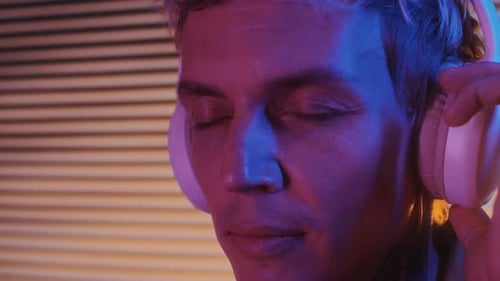 Male DJ Enjoying Music in Headphones in Neon Studio